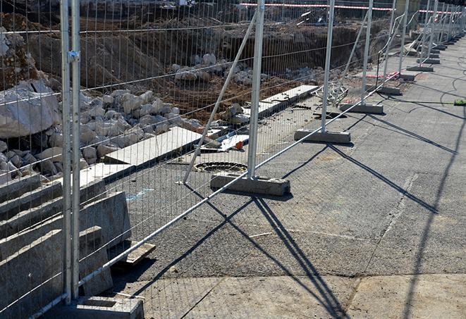 protective barrier made of temporary fence panels being erected around a construction site